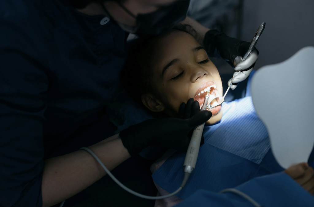 A pediatric dentist gently examines a young child’s teeth for cavities in preschoolers during a routine dental visit.