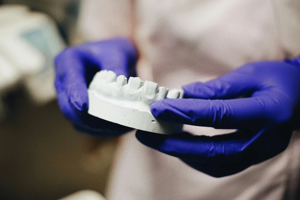  A close-up image of a dental professional holding a model of teeth, demonstrating orthodontic alignment and treatment planning for kids