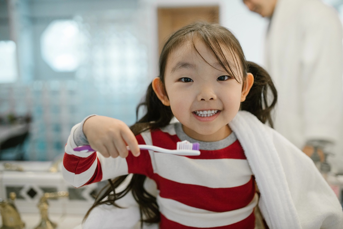 photo of a girl holding a toothbrush and smiling for best toothbrush for kids