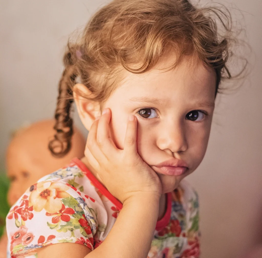 photo of a girl with her hand on her cheek for dental emergency for kids