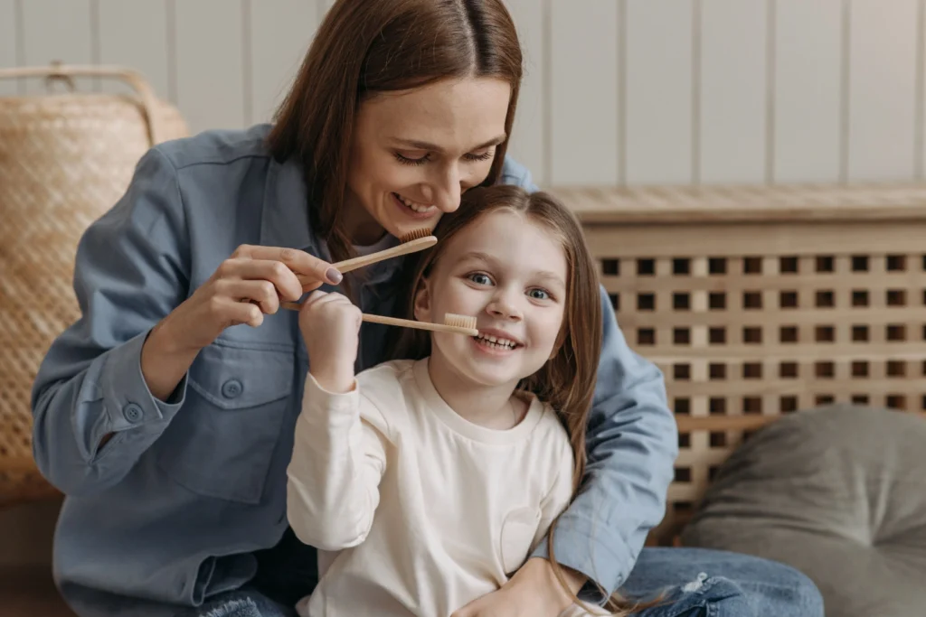photo of a mother and her daughter holding toothbrushes while smiling