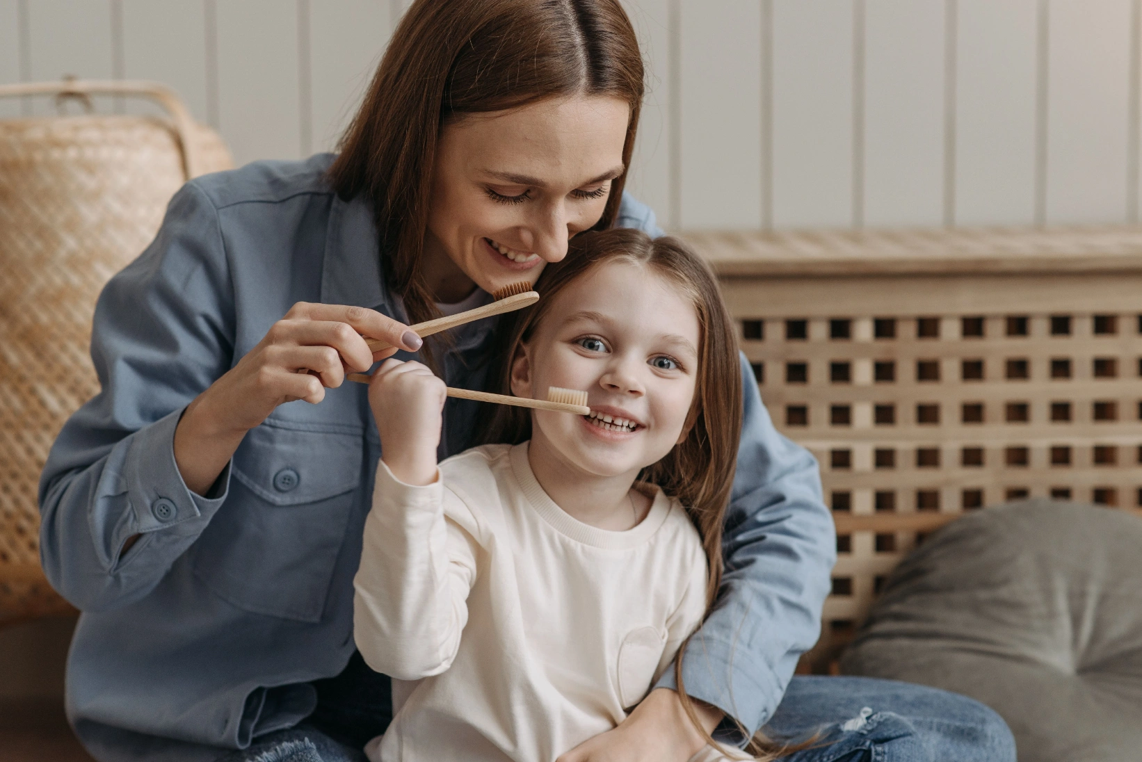 photo of a mother and her daughter holding toothbrushes while smiling