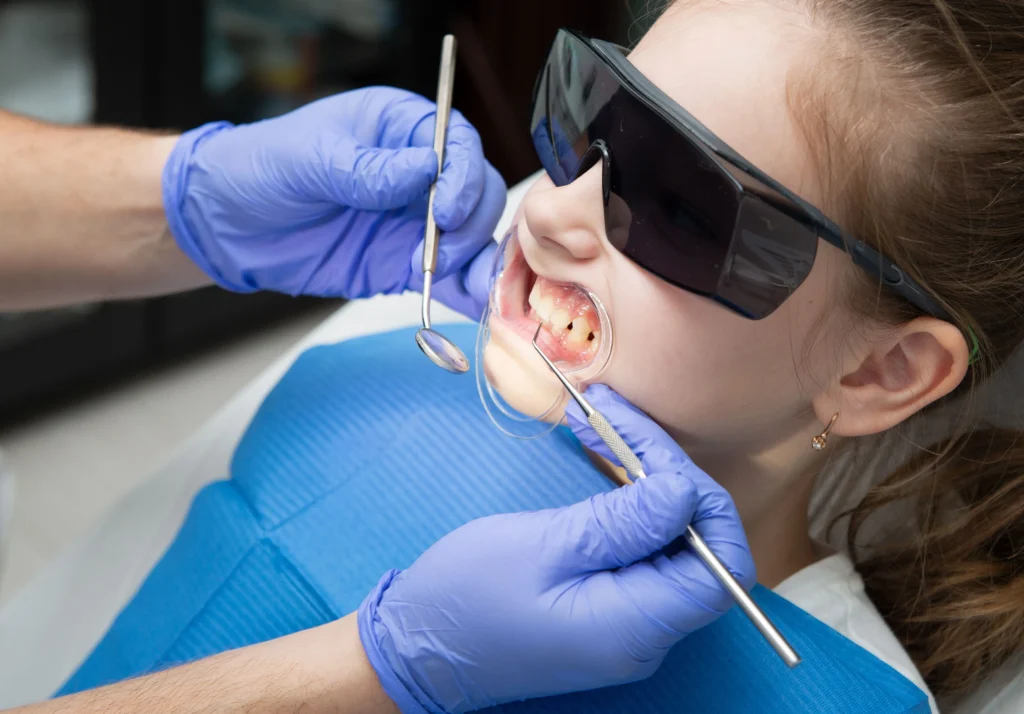 photo-of-a-girl-wearing-protective-eyewear-and-a-mouthguard-as-a-dentist-checks-her-teeth